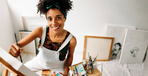istock Happy art painter drawing on a canvas in her art studio 1386186700