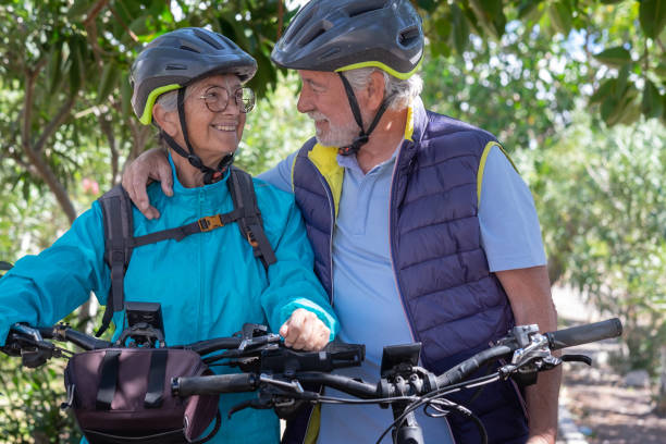 istock Active senior caucasian couple with electrobikes standing outdoors in the park. Two happy elderly people looking in the eyes enjoying nature and healthy lifestyle 1386187568