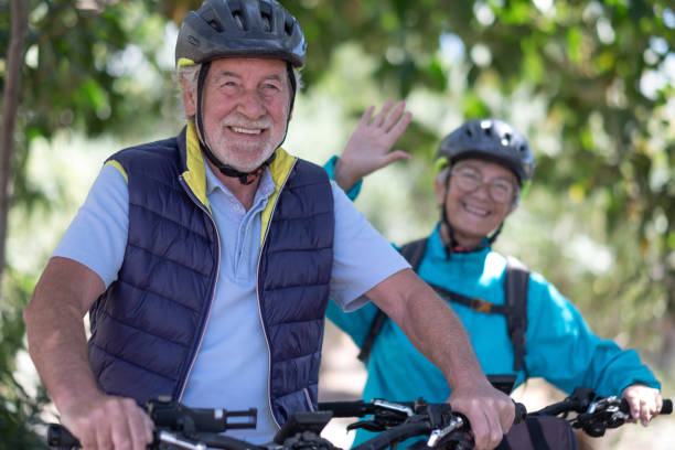 istock Beautiful active senior couple with electrobikes standing outdoors in the park. Two happy elderly people running in nature with their bicycles enjoying healthy lifestyle 1386187630