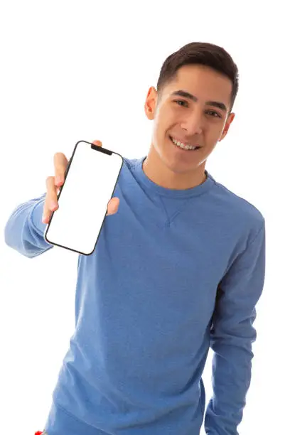 Excited mixed race teenager wearing blue holding mobile phone on cut out white background