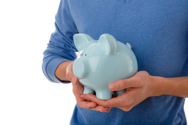 Teenager hand holding blue piggy bank on cut out white background