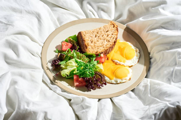 istock Fried eggs with vegetable salad and cheese in a plate on a white sheet. Hard light. 1386188504
