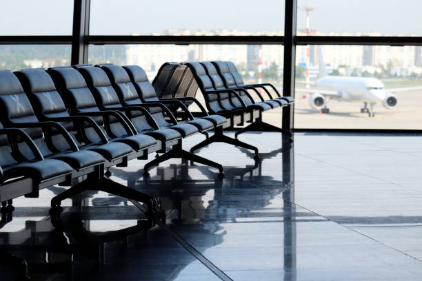 Empty waiting chairs in the airport building against the plane on runway stock photo