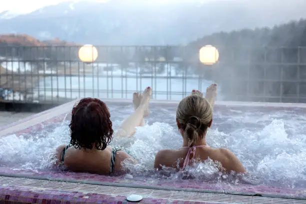 Photo of People, enjoying whirlpool and sauna after day of skiing, relaxing in nice warm whirlpool outdoor, splendid view