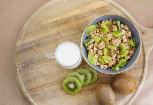 Breakfast with muesli corn flakes and fresh kiwi fruit with milk on wood, Close up day light shot