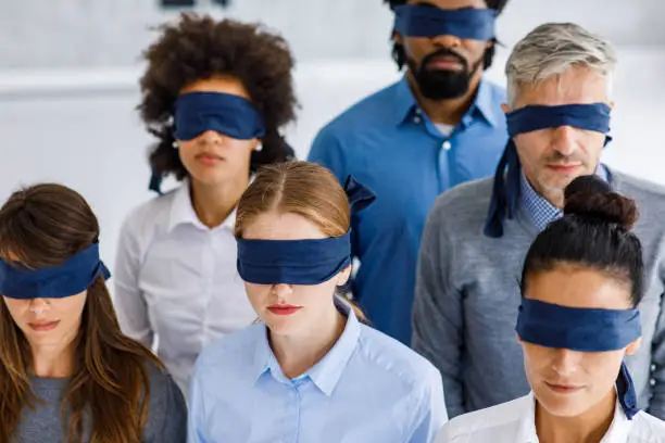 Group of blindfolded business people in the office unable to see the reality.