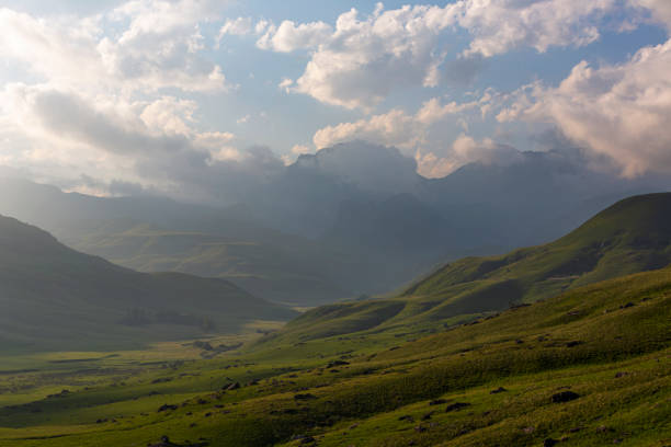 istock Late afternoon clouds over green valley 1386197265