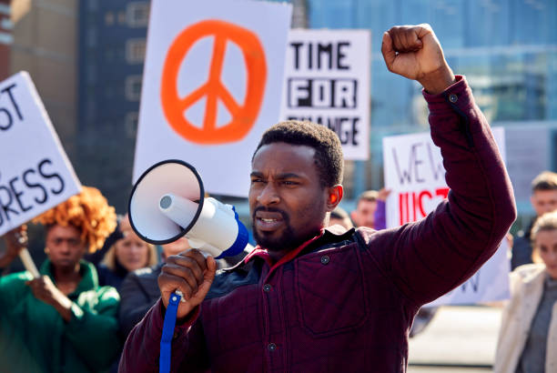 protestors with placards and megaphone on protests demonstration march against racism - sea of tranquility imagens e fotografias de stock