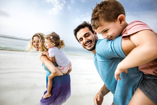 istock Playful family having fun while piggybacking on the beach. 1386199051