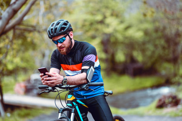 istock Modern Male Cyclist Programming Smartphone For New Route While Riding In Nature 1386199094