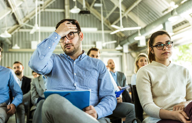 istock Businessman having a headache during an education event in board room. 1386200608