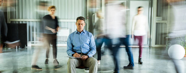 istock Male entrepreneur writing reports surrounded by his colleagues in blurred motion. 1386200653