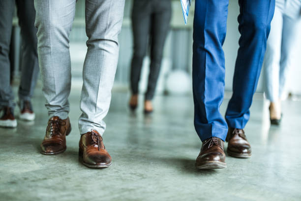 Unrecognizable businessmen walking on the floor in the office while their colleagues are behind them.