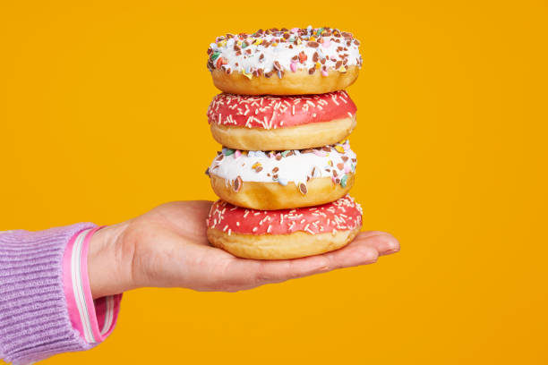 istock Young beautiful woman over yellow background with donuts 1386203934