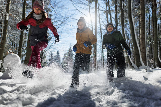 bambini felici che corrono nella bellissima foresta invernale in una giornata di sole - group of people teenager snow winter foto e immagini stock
