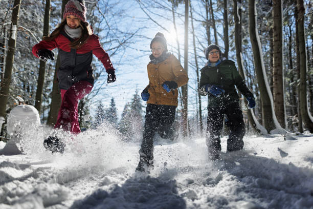 Happy kids running in beautiful winter forest on a sunny day
