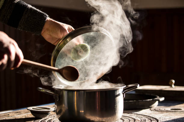 調理鍋から来て、木製のスプーンと混合する蒸気 - vaporization ストックフォトと画像