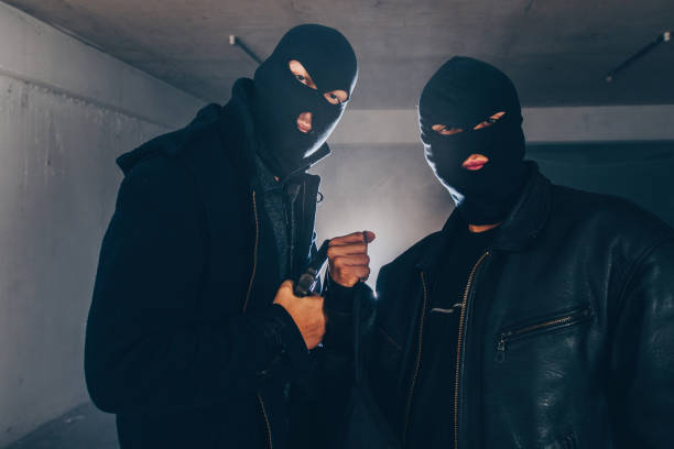 istock Thieves with masks holding gun in dark room 1386207533