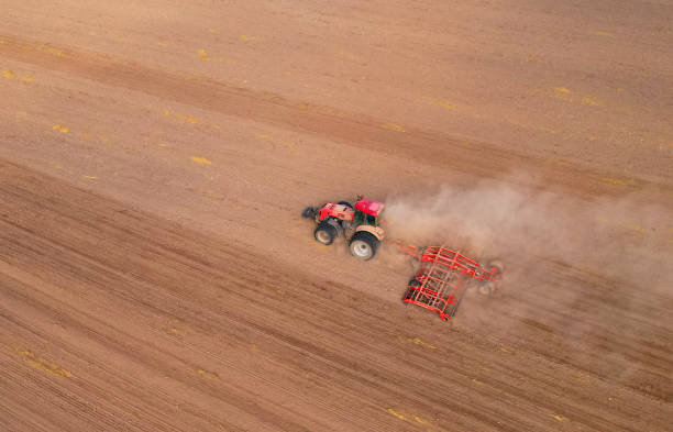 istock Tractor plowing farm field. Tractor with disk harrow on plowing field. 1386208495