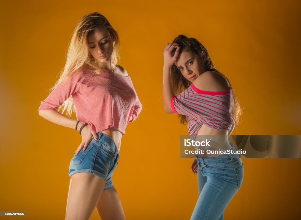 Romantic female friends in trendy clothes standing on yellow background. Carefree girls sending air kisses. - Royalty-free 18-19 Anos Foto de stock Romantic female friends in trendy clothes standing on yellow background. Carefree girls sending air kisses. - Royalty-free 18-19 Anos Foto de stock
