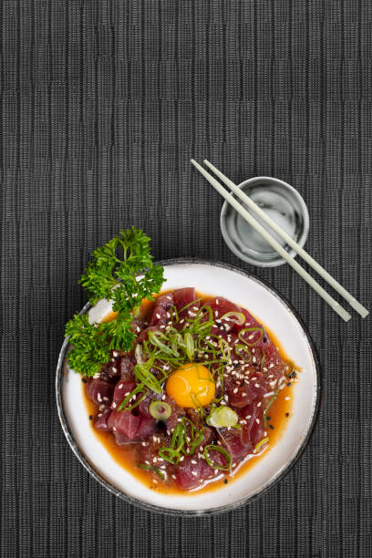 Maguro tuna tartar with sesame chive seaweed and quail egg on Japanese tablecloth with chopsticks stock photo