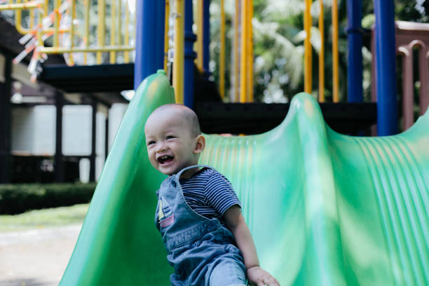 istock One baby boy playing on playground slide 1386210041