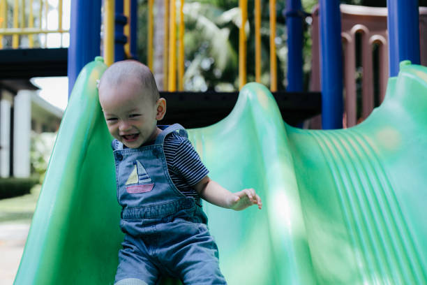 istock One baby boy playing on playground slide 1386210042