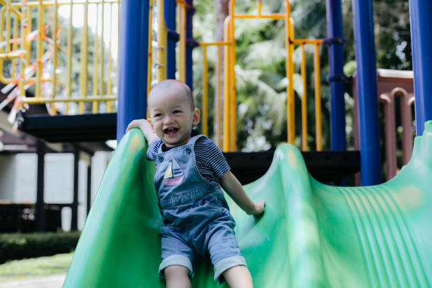 istock One baby boy playing on playground slide 1386210049