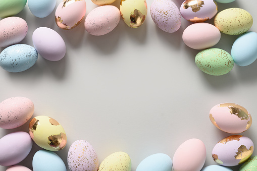 Easter frame with pastel decorative colourful eggs on gray background. View from above. Flat lay. Happy spring greeting card with copy space.