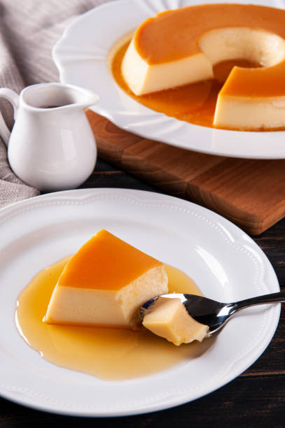 istock Delicious condensed milk pudding on white plate. Someone scooping up a piece with a spoon. 1386212650