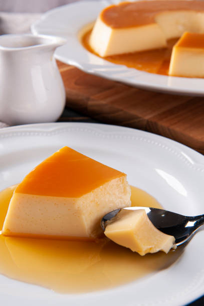 istock Delicious condensed milk pudding on white plate. Someone scooping up a piece with a spoon. 1386212653