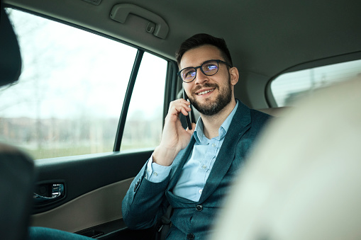 Young businessman in limousine using phone