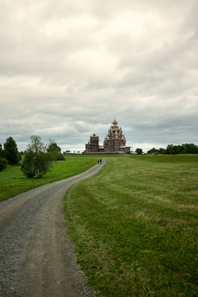 gravel road leads through a field to a wooden orthodox church on the island of kizhi karelia - russia russian culture kizhi island traditional culture imagens e fotografias de stock