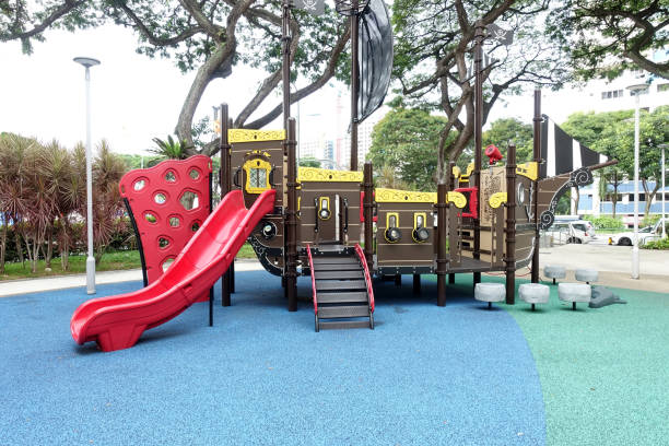 Cute child girl having fun while sliding on slide at the playground during overcast winter day