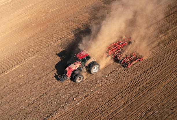 istock Tractor plowing farm field. Tractor with disk harrow on plowing field. 1386226743