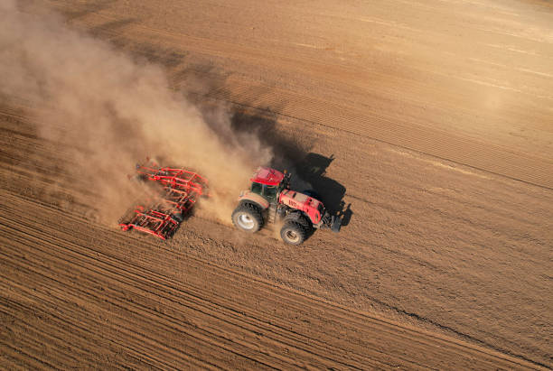 istock Tractor plowing farm field. Tractor with disk harrow on plowing field. 1386228350