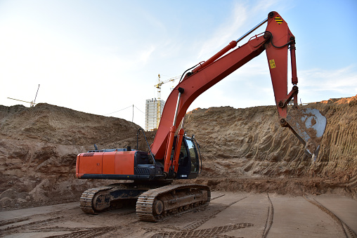 Excavator digging foundation at construction site. Heavy machinery for groungwork. Earthwower on groungwor. House Construction. Excavator on earthworks at construction site. Loader digs ground in pit.