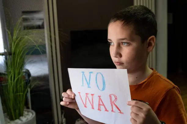 Photo of Slogan of peace without war. Child with message Stop War.