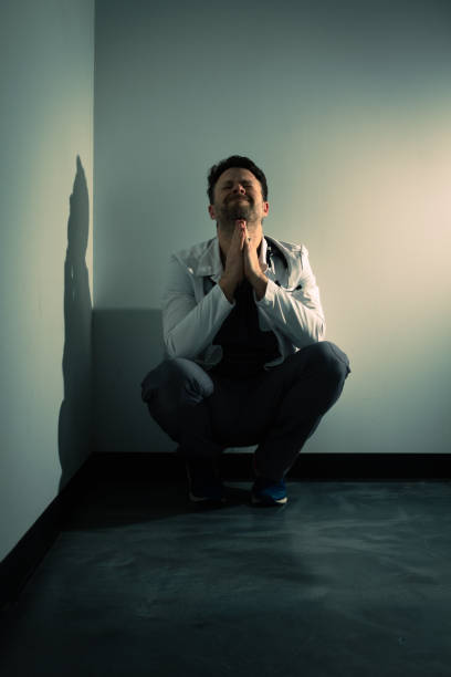istock Tired upset praying doctor in dark hallway 1386232656