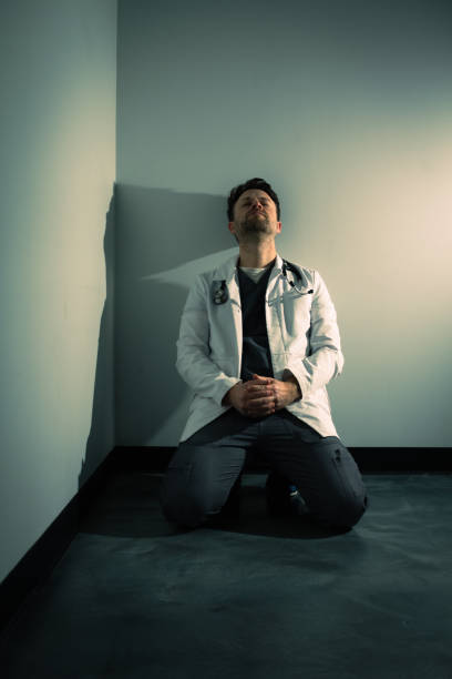 Tired frustrated overworked doctor in dark hallway stock photo