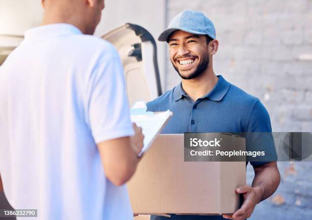 Shot Of A Young Man Receiving His Delivery From The Courier Stock Photo - Download Image Now