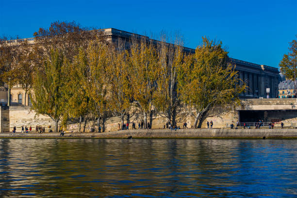 istock Trees With Fall Colors on the Seine Docks in Paris With Peoples Walking 1386234734
