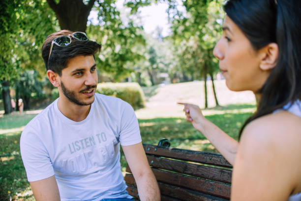 istock Romantic young couple sitting on park bench together 1386235601