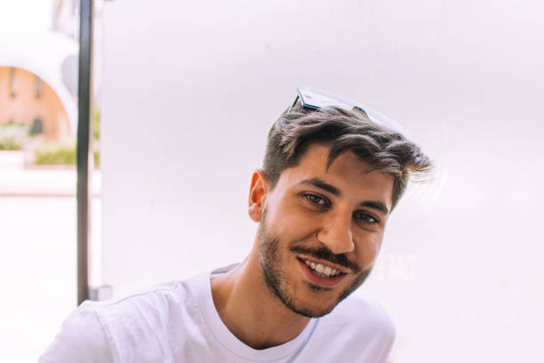 istock Cheerful young man sitting in coffee shop 1386235602