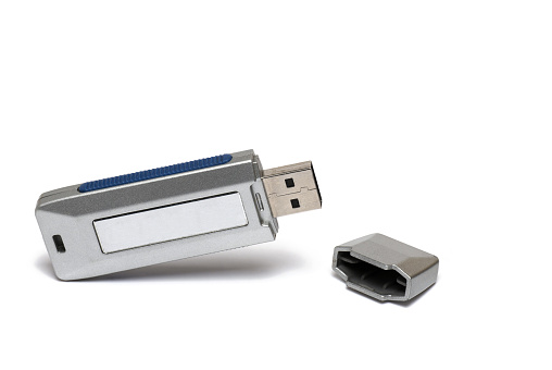 Close up of opened silver USB flash drive stick data storage device with lid next to it on white background