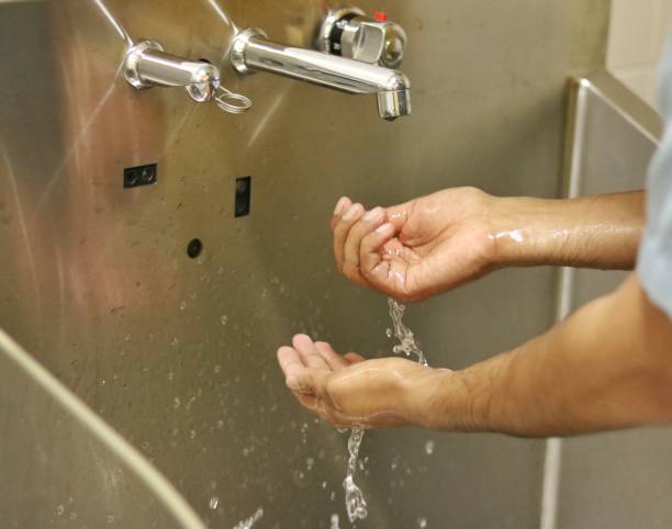 istock Washing hands in dedicated scrub area of operation room. 1386240218