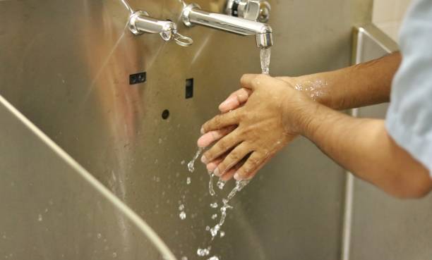 istock Washing hands with running water after applying surgical scrub solution in a scrub area of operation room. 1386240231