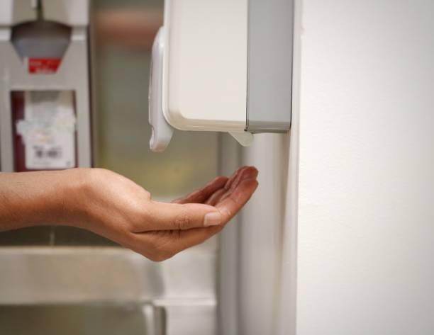 istock Palm under an automatic wall mounted sanitizer dispenser. 1386240246