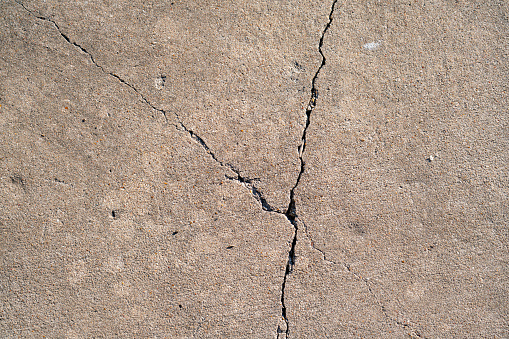 Cracked concrete wall in a gray color.