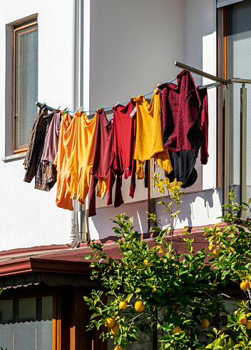 Colorful men's clothes drying by hanging on the ropes on the balcony.